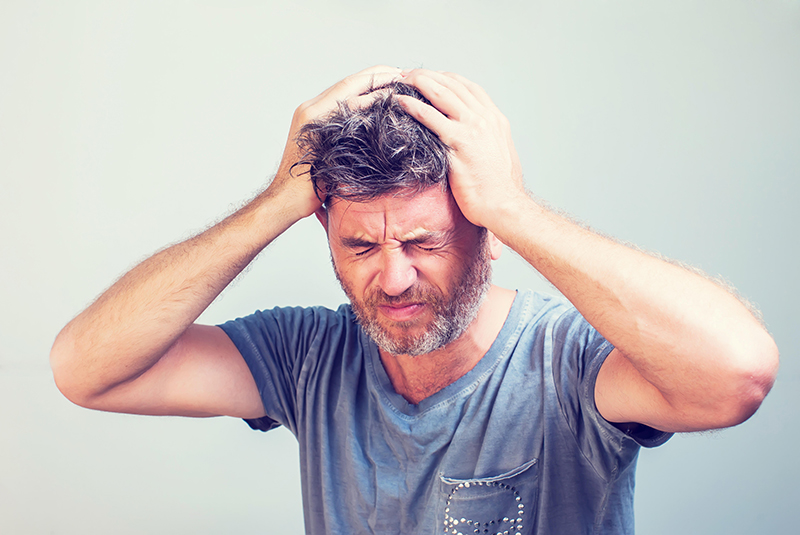 Guy holding head with headache